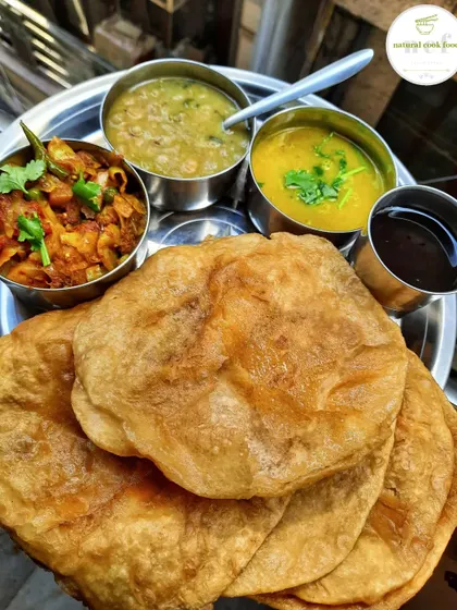 A traditional Manipuri breakfast of Tal (puri) served with ooti, lentil curry, cabbage fry, and black tea.