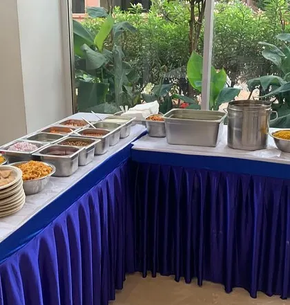 A full chaat counter setup for a birthday party. This L-shaped arrangement allows for easy access and a wide variety of toppings for guests to enjoy.