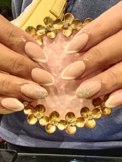 A chic and understated design with a neutral beige base, a fine white reverse French line, and glitter accent nails.