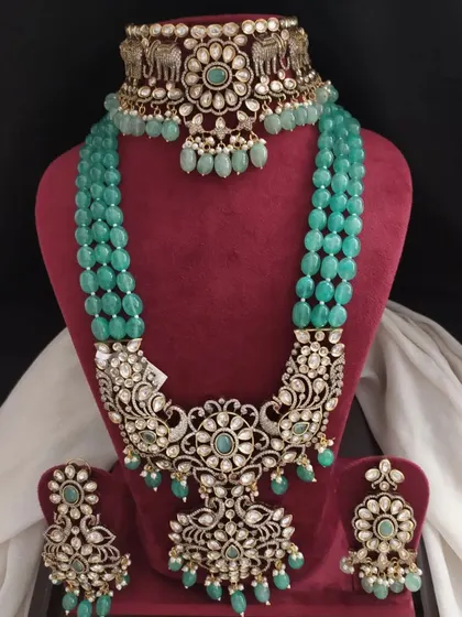An opulent Victorian set in emerald green with intricate floral and peacock designs. The detailed craftsmanship gives it the look of fine, heirloom jewellery.