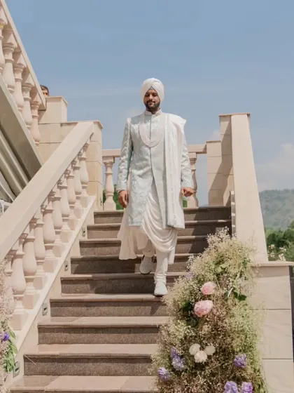 The groom's majestic descent down the grand staircase at Raffles Udaipur, ready for his wedding ceremony.