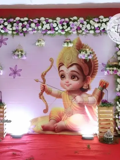 The full stage for the Ram Lalla themed naming ceremony. The combination of the large backdrop, floral frame, and balloon columns creates a complete and immersive theme.