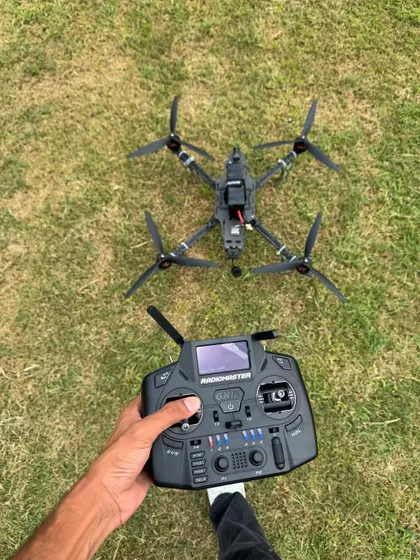 A point-of-view shot showing a completed FPV drone and the radio controller used to fly it. This is the setup you will become an expert at handling.
