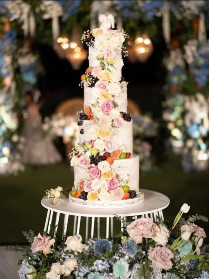 A magnificent multi-tiered wedding cake adorned with fresh flowers and fruits. I work with the best bakers to create cakes that are both delicious and a work of art.