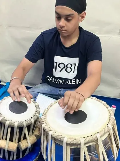 One of our young students practicing on a newly delivered professional tabla set. We take pride in providing instruments that support the growth of aspiring musicians.