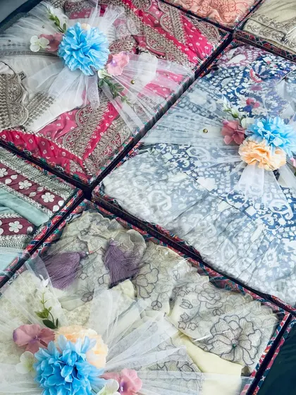 A collection of baby shower gifts, featuring beautifully packed outfits in a blue and white floral theme.