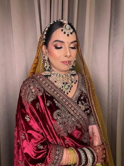 A bride adorned in sunset hues. This look showcases the art of enhancing beauty, with a focus on creating a warm, glowing look that complements the rich velvet of her outfit.