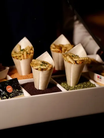 A server's tray elegantly arranged with cones of seasoned fries and dipping sauces.