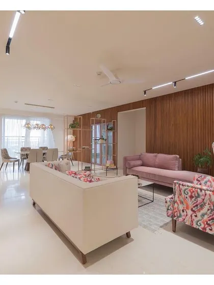 Another view of the living area, highlighting the combination of a plush sofa, a patterned wingback chair, and the warm fluted wood wall. The lighting is designed to be functional and create a warm, inviting ambiance.