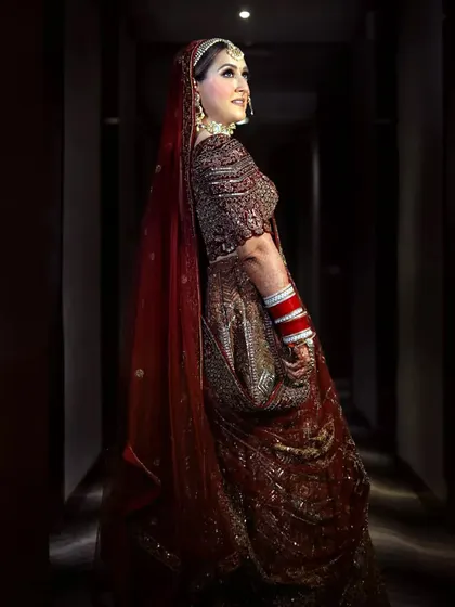 A full-length portrait of the bride in a corridor, her elegant pose and stunning lehenga creating a timeless image.