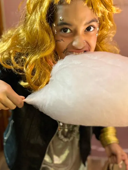 This ghostly rockstar with a wild wig and cool jacket takes a big bite of candy floss. Costumes and treats are the best combination.