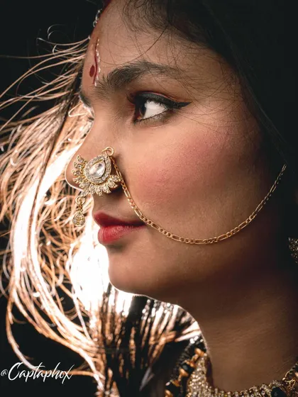 A detailed close-up from a creative shoot, focusing on traditional jewelry and expressive features. The rim lighting beautifully highlights the hair, adding a sense of motion and drama to this profile shot.