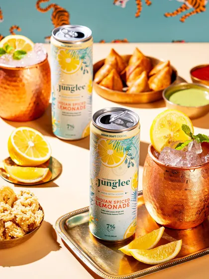 A styled shot of canned lemonade with Indian snacks like samosas, creating a perfect pairing suggestion.