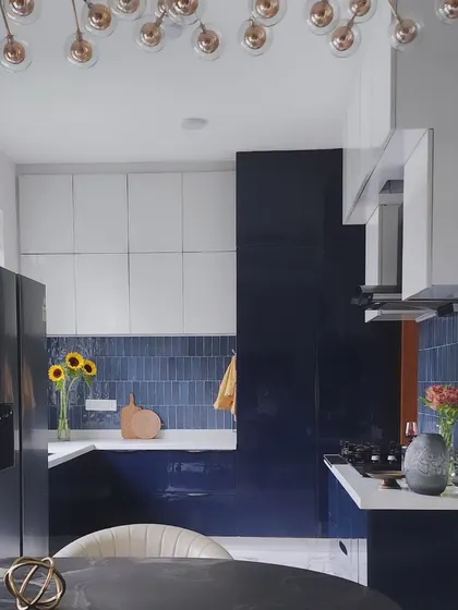 The open kitchen features a vibrant blue subway tile backsplash, creating a lively contrast against the white upper cabinetry. A large window floods the workspace with natural light, making it a bright and functional area.