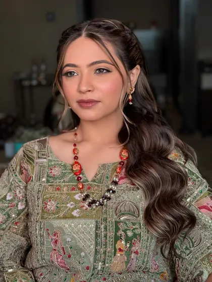 The bride's Mehendi look from another angle, showcasing the soft waves in her hair and the flawless finish of her makeup.