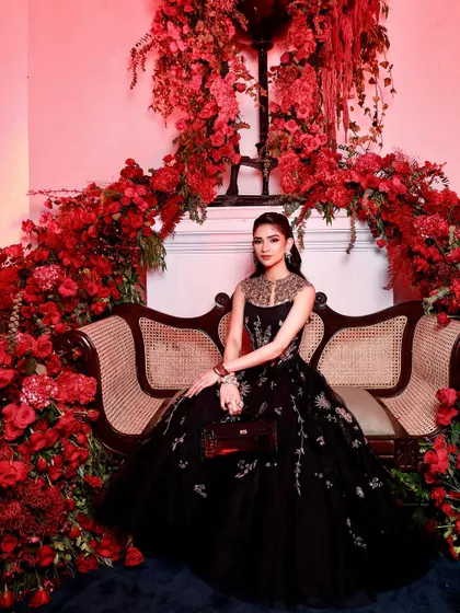 Another stunning portrait against the floral wall. The red lighting adds a dramatic flair, making the makeup look even more striking and glamorous.
