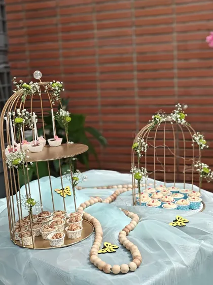 We bring the sweetness to your celebration with our elegant dessert table setups. This display, featuring a variety of our cupcakes and treats in decorative birdcages, was designed for a beautiful outdoor party.