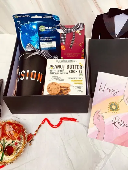 A dapper gift for a dapper brother. This Rakhi hamper comes in a tuxedo-themed box and is filled with men's grooming products, a mug, and cookies.