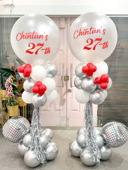 Double the fun for Chintan's 27th! This pair of matching balloon columns in a striking red, white, and silver theme features large personalized balloons and disco balls for a fun, party-ready look.