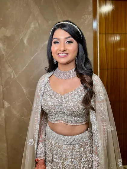 A modern and chic look for an engagement or reception. The bride wears a silver-grey lehenga with a cape, and her makeup is kept fresh and minimal with a simple headband.