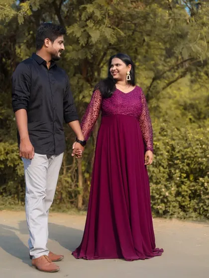 A romantic walk in the park. The groom's casual attire perfectly balances the elegance of the bride's lace-sleeved, wine-colored gown.