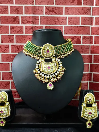 This green beaded choker set with a large kundan pendant is a stunning rental option. The matching earrings complete this elegant and colorful look.