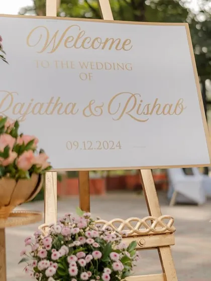A simple and elegant welcome sign for a pastel-themed wedding, surrounded by beautiful pink flowers.