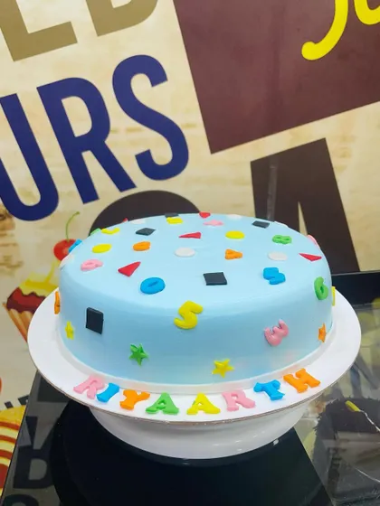 A 1.5kg cake with a simple design featuring colorful letters and shapes.