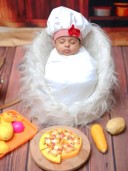 A full view of the 'Little Chef' setup, with the newborn surrounded by toy foods and kitchen props.