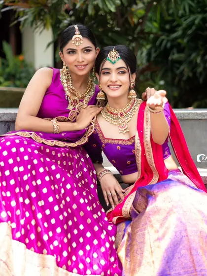 A perfect example of bridesmaid goals, featuring two coordinated half sarees in shades of purple and pink with rich brocade work.