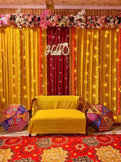 I offer a variety of styles for your functions. This modern Haldi setup features a clean yellow backdrop with elegant fairy lights and a custom 'Haldi' neon sign, blending tradition with a contemporary touch.