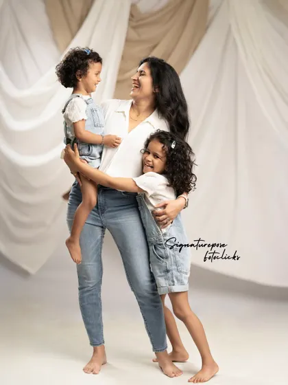 A mother shares a happy, candid moment with her two daughters, showcasing the natural and loving bond between them.
