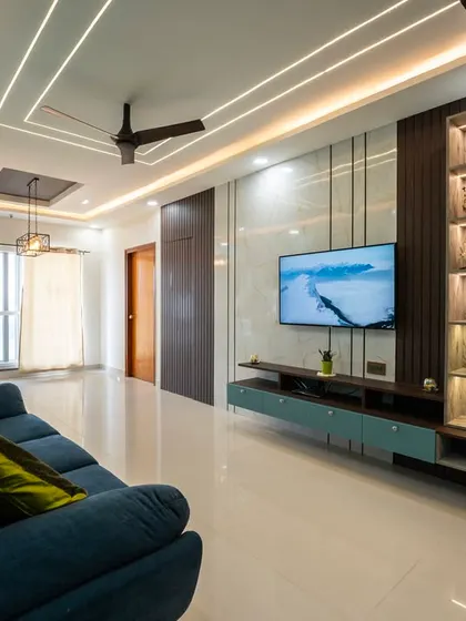 A glimpse into the living room designed for Praveen and Pratyusha, showcasing a cozy mix of sleek blue accents, warm wood tones, and soft lighting that creates an inviting ambiance.