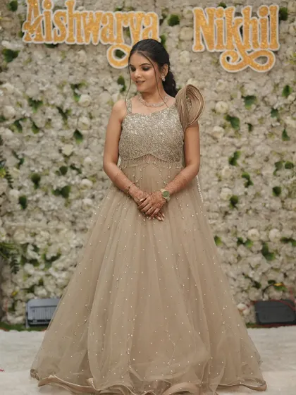 A full-length view of the bride's stunning beige engagement gown with intricate beadwork. The makeup is sophisticated and polished.