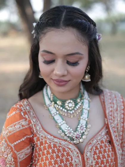 A detailed shot of the eye makeup and stunning layered jewelry. The soft cut crease and defined lashes make her eyes the star of the show.