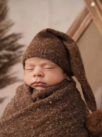 This shot captures the full setup of the camping theme, with the baby swaddled comfortably and the rustic props creating a warm, earthy feel.