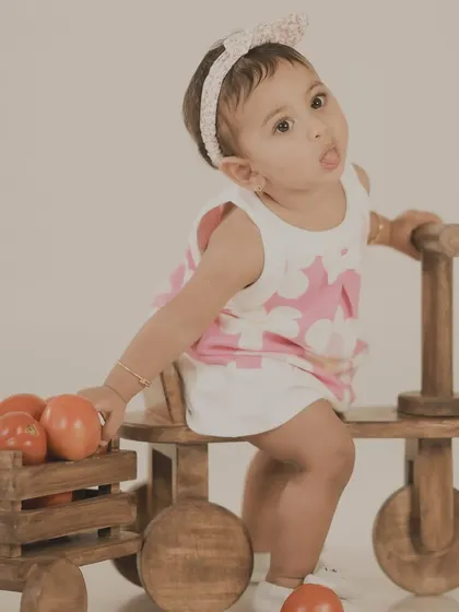 A cute baby girl playing with tomatoes on a wooden tricycle. A simple and sweet concept for a fun photoshoot.
