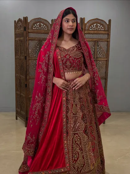 This deep red velvet lehenga features intricate paisley and floral embroidery, perfect for a winter wedding.