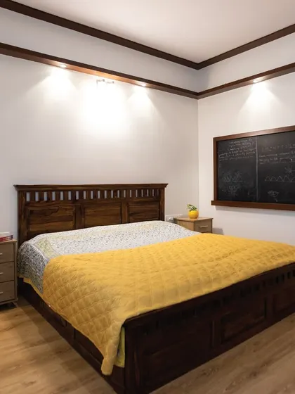 Another shot of the grown-up kid's room, focusing on the solid wood bed with built-in storage. The blackboard wall adds a fun, interactive element to the sophisticated design.