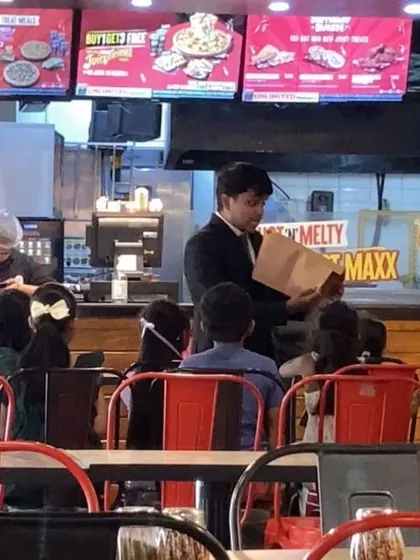 Performing a trick at a restaurant, with kids and parents watching intently. I can set up my show in various commercial venues, making me a versatile choice for event planners.