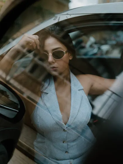 A creative portrait shot through a car window. The reflections and the model's pose create an artistic and moody fashion image.