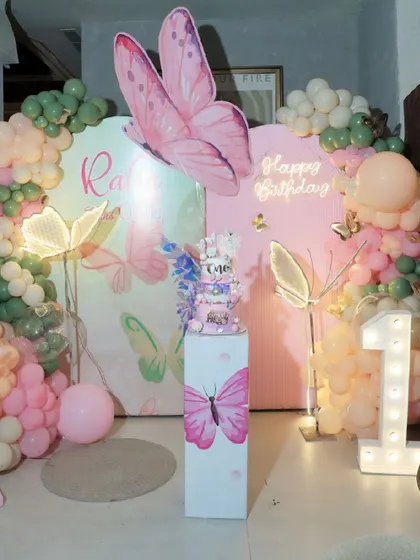 A closer look at this butterfly-themed cake-cutting stage. The setup includes a large marquee '1', a custom pedestal for the cake, and glowing butterfly props that bring a touch of magic to the celebration.