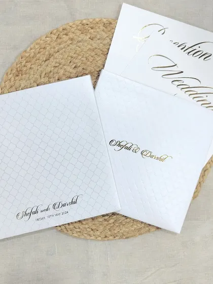 A premium and elegant wedding invitation suite in pure white, featuring a subtle texture and clean gold foil typography.