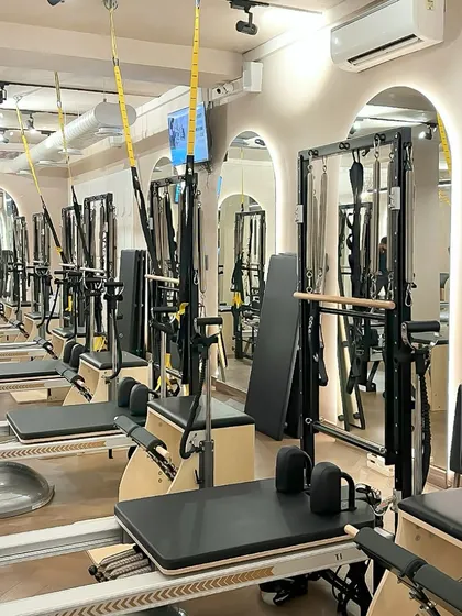 The view of our studio, lined with reformers and Cadillacs. The arched mirrors and warm lighting create an atmosphere of focused energy.