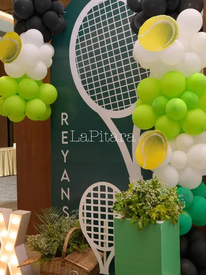 A welcome sign and balloon arrangement in green, white, and black, perfectly matching the modern tennis theme.