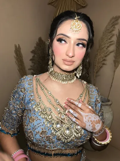 A side profile showcasing the soft, romantic updo and the delicate white henna design.