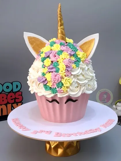 A giant cupcake designed to look like a unicorn, with a beautiful swirl of rainbow-colored frosting.