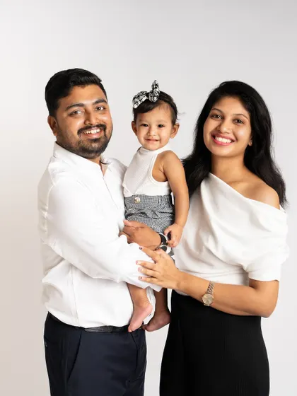 A picture-perfect family of three. Their coordinated black and white outfits create a classic and polished look for this studio family portrait.