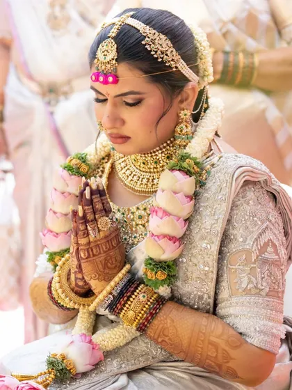 The bride during a prayer ritual, with her hands joined. The dark stain on her palms is prominent and looks incredibly auspicious.