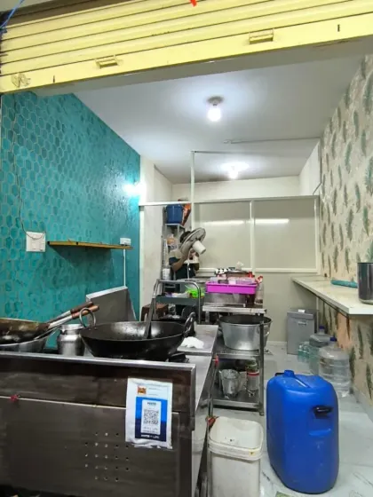 Wallpaper installation in a commercial kitchen or small restaurant, combining a teal honeycomb pattern with a peacock feather design.
